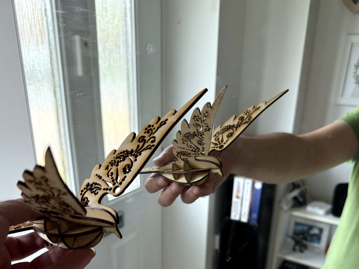 Pair of laser-cut wooden doves with detailed engraved wings